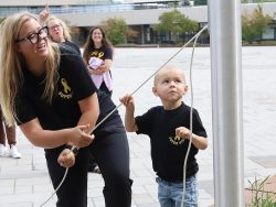 A volunteer and child enjoy a ribbon and bubble activity at a community event.